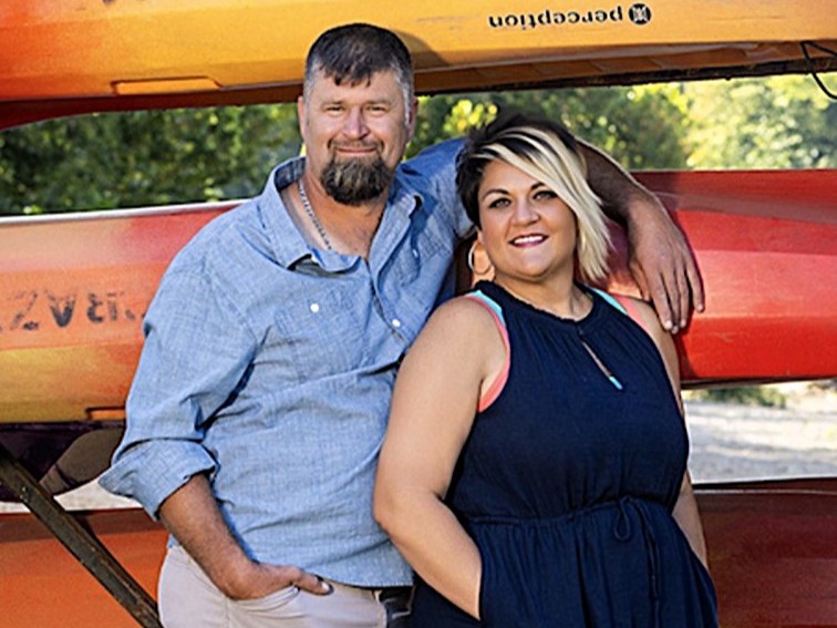 Mason and Becky Jones leaning against a rack of kayaks