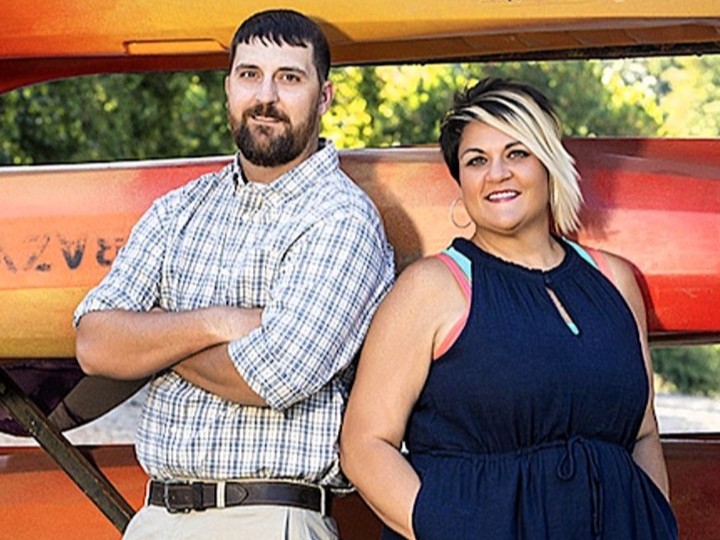 Jesse and Candi Luedeke in front of a rack of kayaks