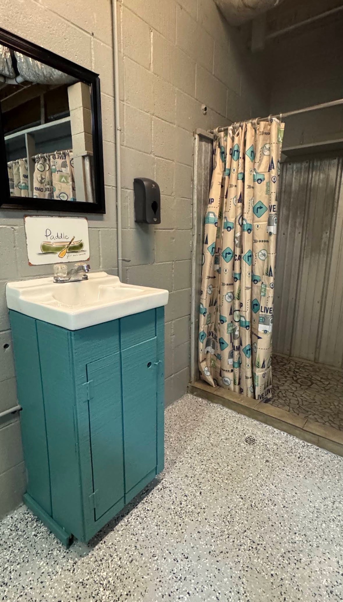 A curtained shower and teal vanity inside the main shower house
