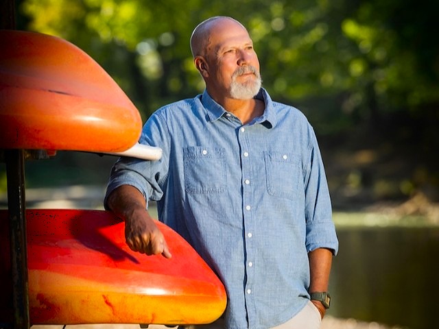 Bobby Jones leaning against a rack of kayaks by the Buffalo River