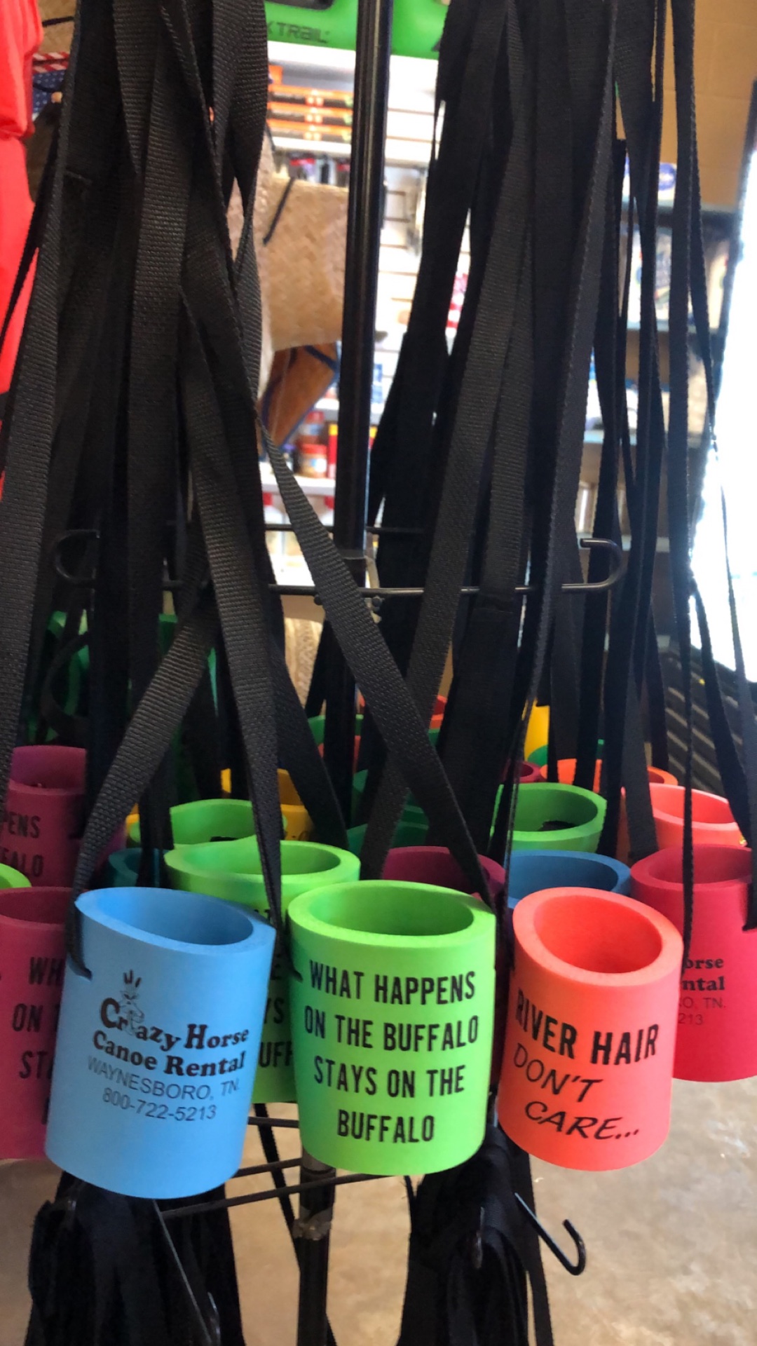 Colorful can koozies with river sayings hanging on a rack