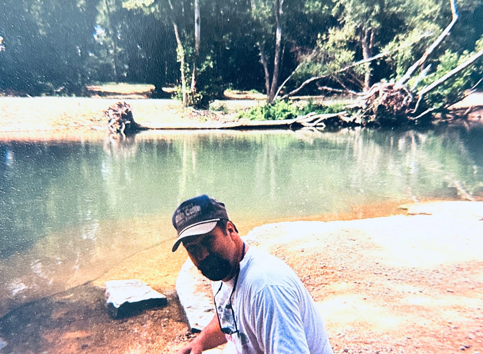 Dad kneeling on a gravel bar beside a clear green stretch of the Buffalo River