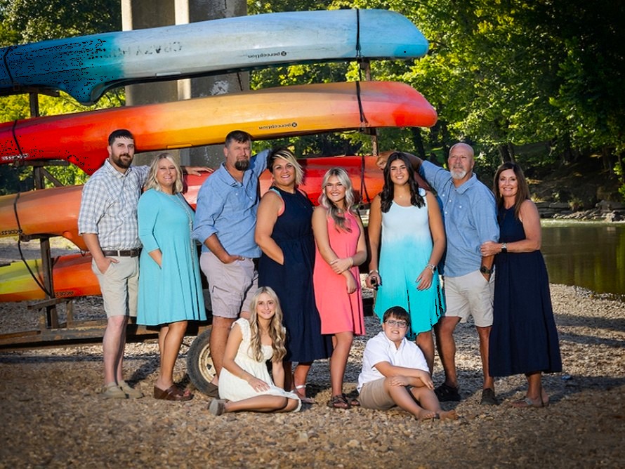 The Crazy Horse family in front of a rack of canoes and kayaks by the Buffalo River