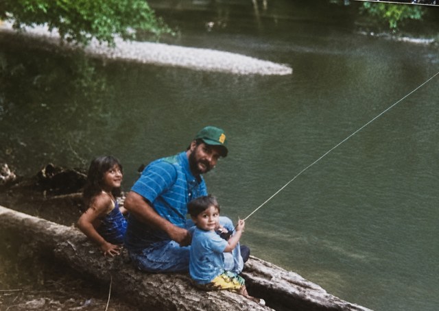 Dad fishing with his two kids on a fallen log along the Buffalo River