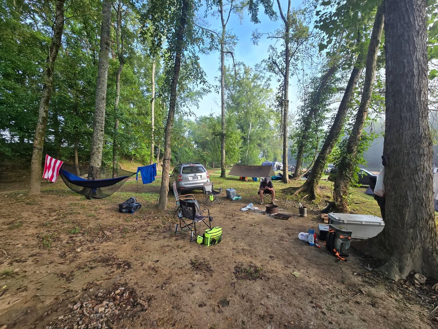 Hammock, chairs and coolers set up at a riverfront campsite