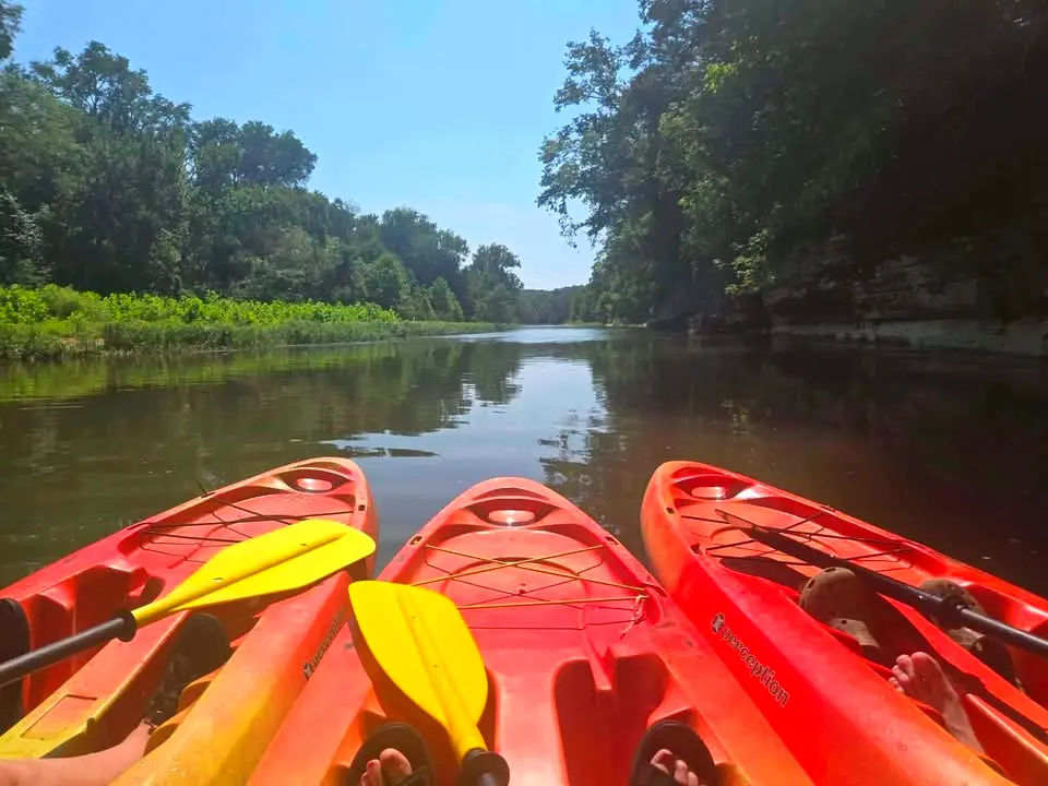 Three kayaks drifting side by side on flat water